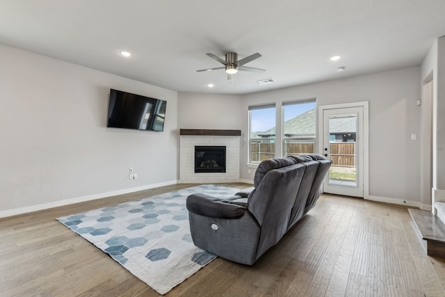 living room featuring baseboards, visible vents, wood finished floors, a fireplace, and recessed lighting