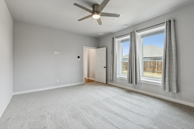 empty room with carpet floors, a ceiling fan, and baseboards