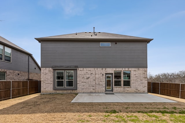 rear view of property featuring a patio area, brick siding, a fenced backyard, and a lawn