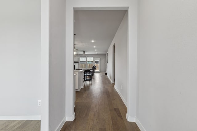 corridor featuring baseboards, dark wood finished floors, and recessed lighting