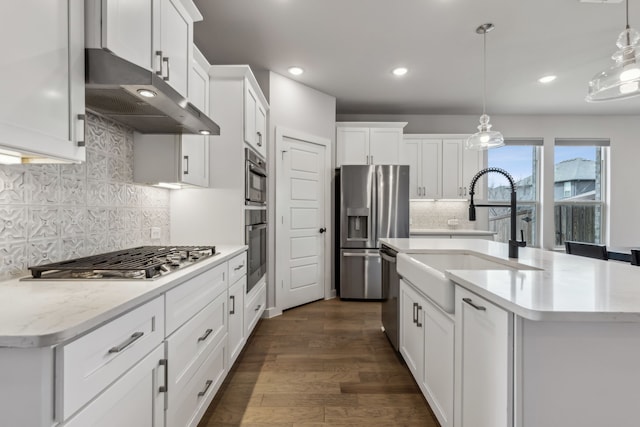 kitchen featuring a center island with sink, white cabinets, appliances with stainless steel finishes, under cabinet range hood, and a sink