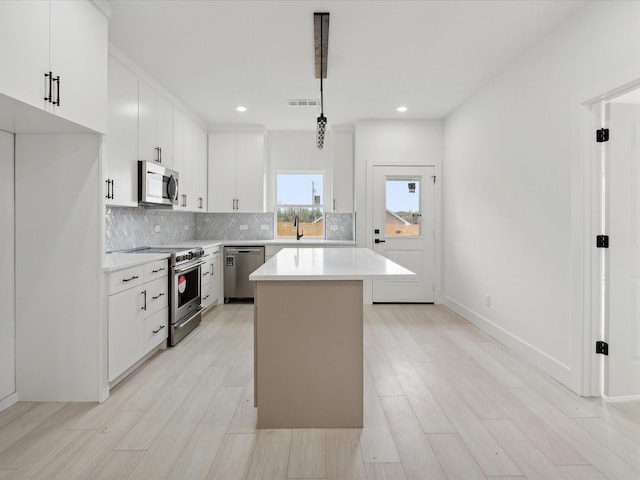 5809 Black Pine Cir, Granbury, TX 76048 - kitchen with stainless steel appliances, light countertops, backsplash, a kitchen island, and white cabinetry