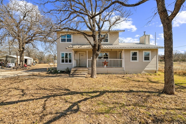 traditional home with a porch, metal roof, and a chimney