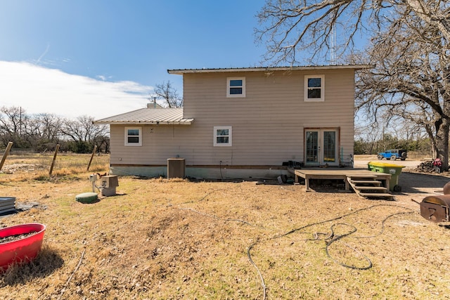 rear view of house with central air condition unit, a deck, metal roof, and french doors