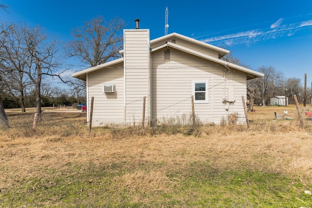 view of property exterior with a wall mounted air conditioner and a chimney