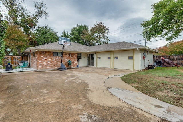 view of front of house featuring driveway, an attached garage, fence, central AC, and brick siding