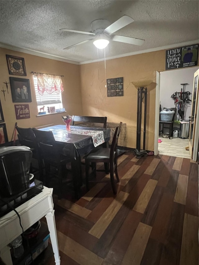 dining space with ceiling fan, ornamental molding, a textured ceiling, and wood finished floors