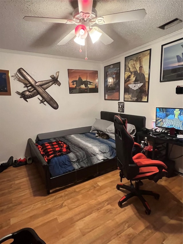 bedroom with a textured ceiling, ornamental molding, and wood finished floors