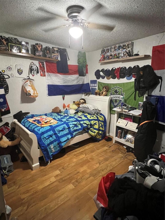 bedroom with a textured ceiling, a ceiling fan, and wood finished floors