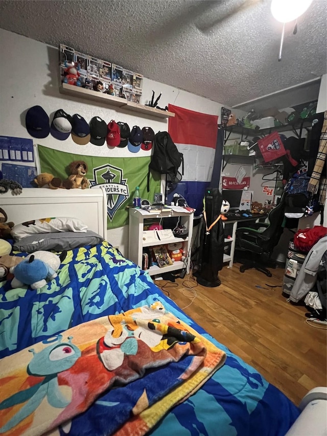 bedroom featuring a ceiling fan, a textured ceiling, and wood finished floors