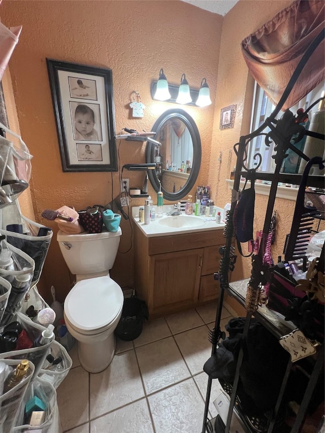 bathroom featuring toilet, vanity, and a textured wall