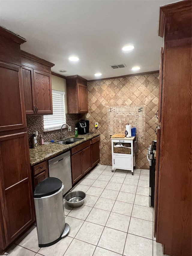 kitchen with visible vents, dark stone countertops, stainless steel dishwasher, a sink, and light tile patterned flooring