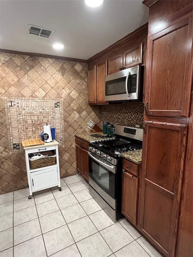 kitchen featuring appliances with stainless steel finishes, dark stone counters, visible vents, and light tile patterned floors