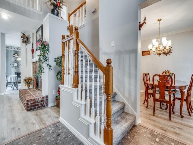 stairway featuring baseboards, a high ceiling, tile patterned flooring, crown molding, and a chandelier