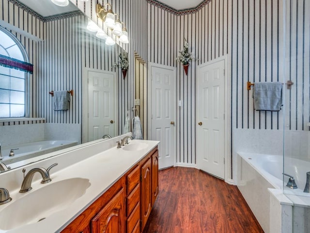 full bath featuring a sink, a bath, and wallpapered walls