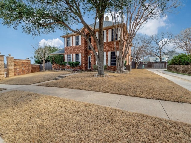 colonial-style house with a gate, fence, brick siding, and central AC