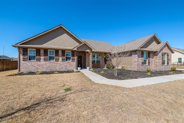 view of front facade with brick siding, a front yard, and fence