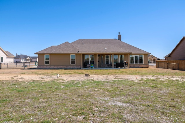 back of property with a gate, a patio, a fenced backyard, a yard, and a chimney