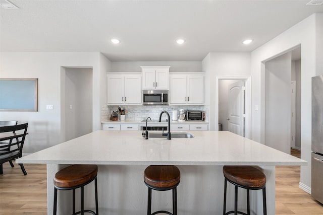 kitchen with backsplash, appliances with stainless steel finishes, a kitchen bar, and a sink