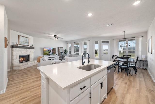 kitchen featuring dishwasher, a fireplace, light wood finished floors, and a sink