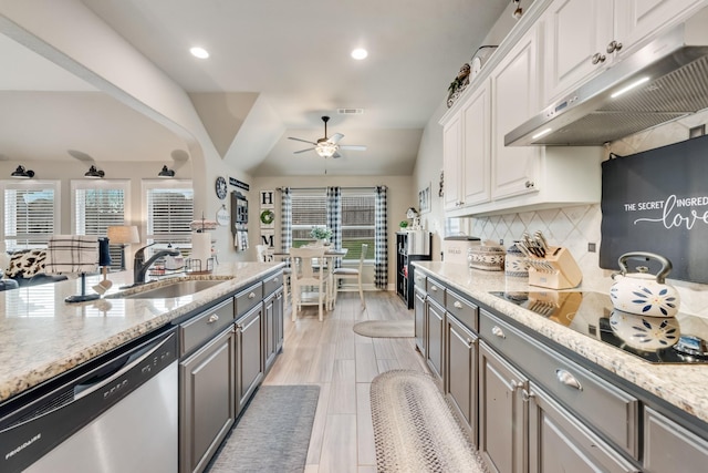 kitchen with under cabinet range hood, a sink, white cabinets, stainless steel dishwasher, and decorative backsplash