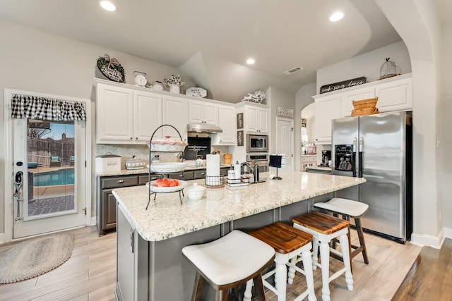 kitchen with arched walkways, visible vents, backsplash, appliances with stainless steel finishes, and under cabinet range hood