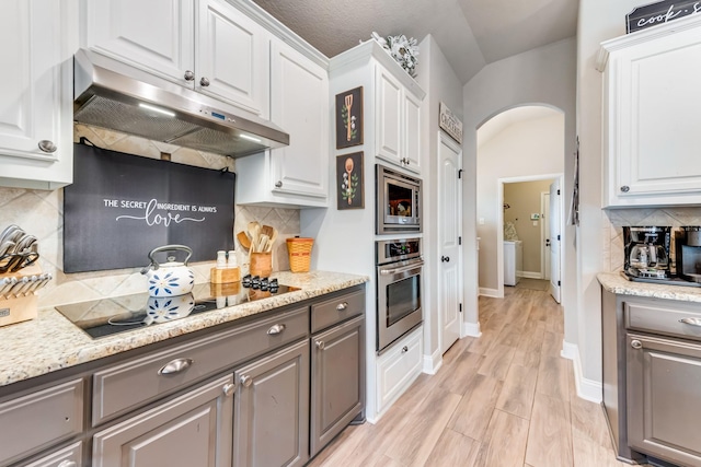 kitchen featuring stainless steel appliances, arched walkways, gray cabinets, and under cabinet range hood