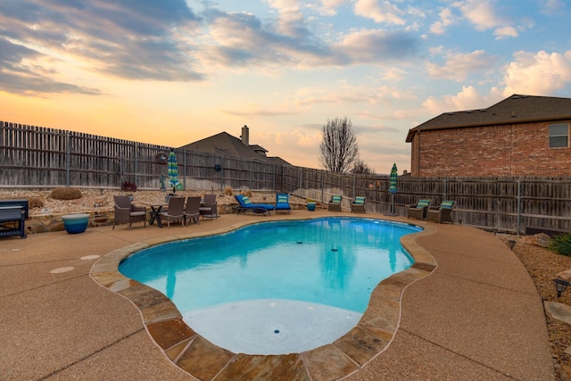 pool at dusk with a patio area, a fenced backyard, and a fenced in pool