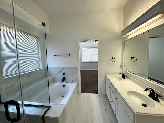 full bath with marble finish floor, double vanity, a sink, and a bath