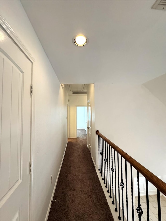 hall with attic access, baseboards, and light colored carpet