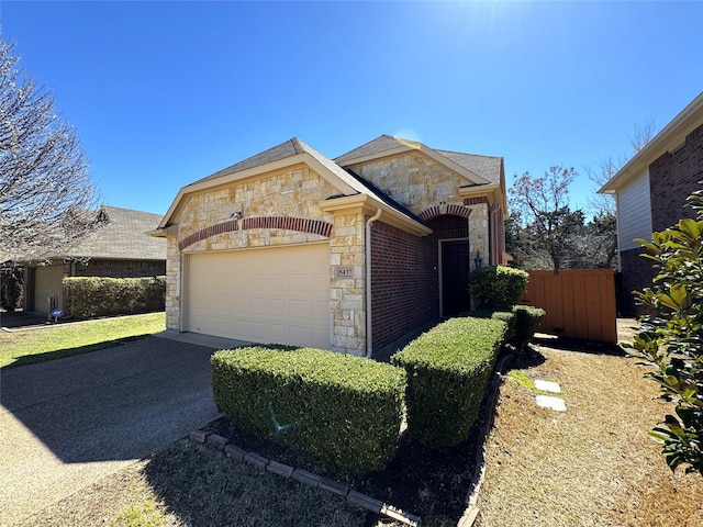 view of front of house with a garage, stone siding, driveway, and fence