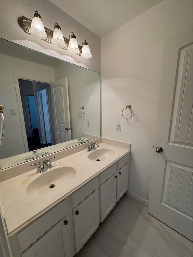 full bath featuring double vanity, marble finish floor, and a sink