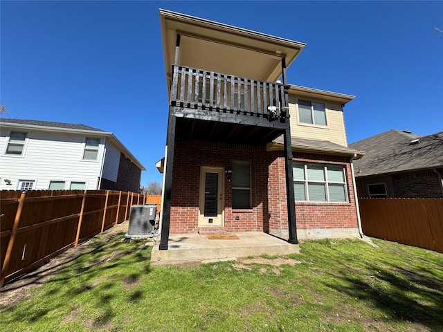 rear view of property with a yard, a fenced backyard, a patio area, and brick siding