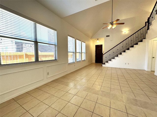 unfurnished living room featuring light tile patterned floors, a ceiling fan, lofted ceiling, stairs, and a decorative wall