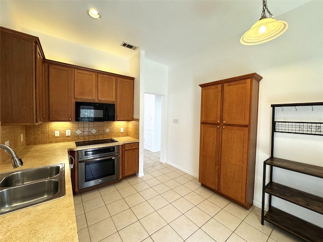 kitchen with tasteful backsplash, visible vents, light countertops, black appliances, and a sink