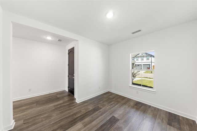 unfurnished room featuring baseboards, visible vents, and dark wood finished floors