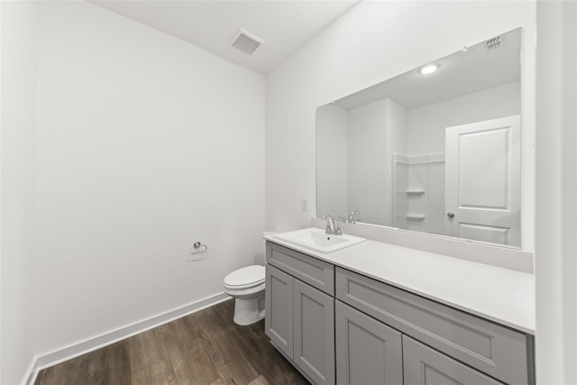 bathroom with baseboards, visible vents, toilet, wood finished floors, and vanity