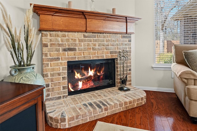 room details featuring a brick fireplace, baseboards, and wood finished floors