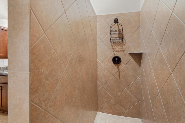 interior details featuring tiled shower and vanity