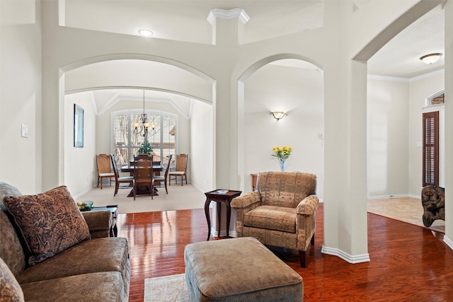 living room featuring an inviting chandelier, baseboards, ornamental molding, and wood finished floors