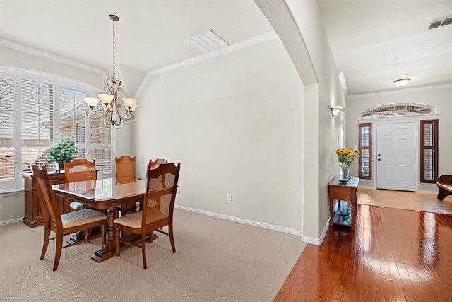 dining room featuring ornamental molding, arched walkways, wood-type flooring, and visible vents