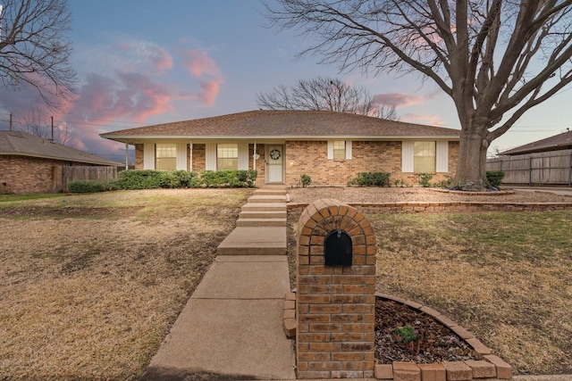 single story home with a yard, brick siding, fence, and a shingled roof