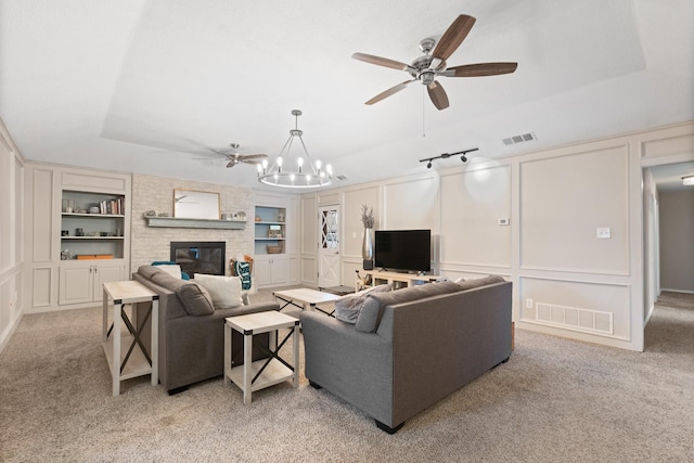 living area with built in shelves, a tray ceiling, visible vents, and a decorative wall