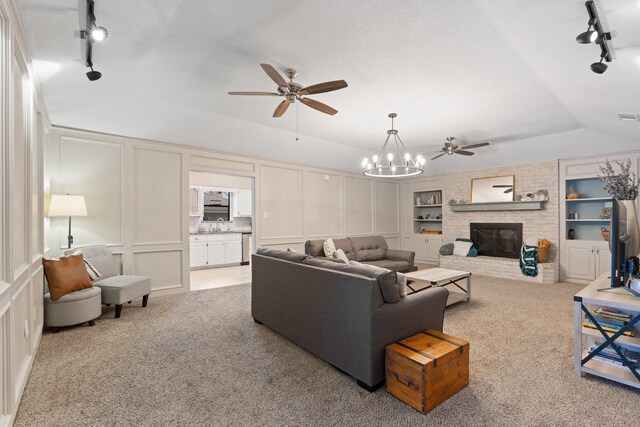 living area with light carpet, rail lighting, built in shelves, and a decorative wall