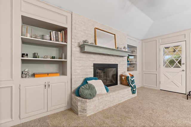 carpeted living area featuring lofted ceiling, a fireplace, and built in features