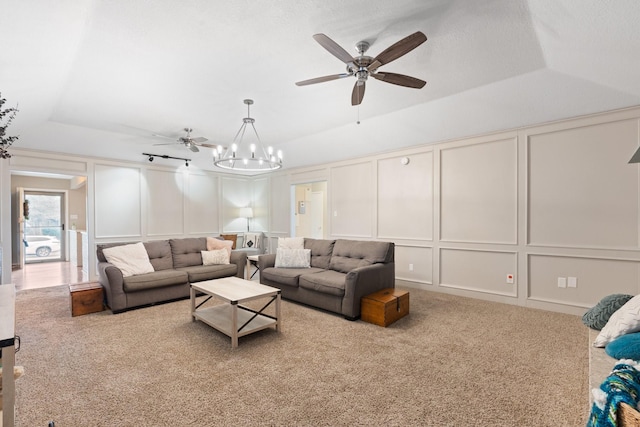 living room with carpet, a decorative wall, a tray ceiling, and ceiling fan