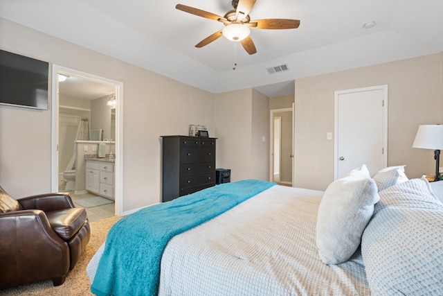 bedroom with light tile patterned floors, visible vents, a raised ceiling, a ceiling fan, and ensuite bath