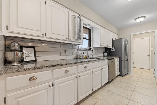 kitchen featuring light tile patterned floors, stainless steel appliances, a sink, and white cabinets