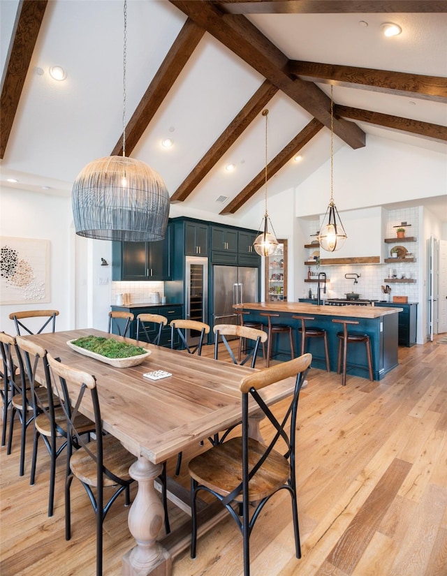 dining space with light wood finished floors, high vaulted ceiling, and beam ceiling