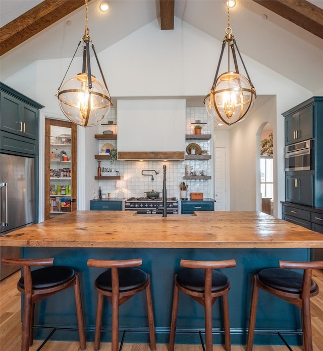 kitchen with arched walkways, butcher block countertops, appliances with stainless steel finishes, and custom range hood